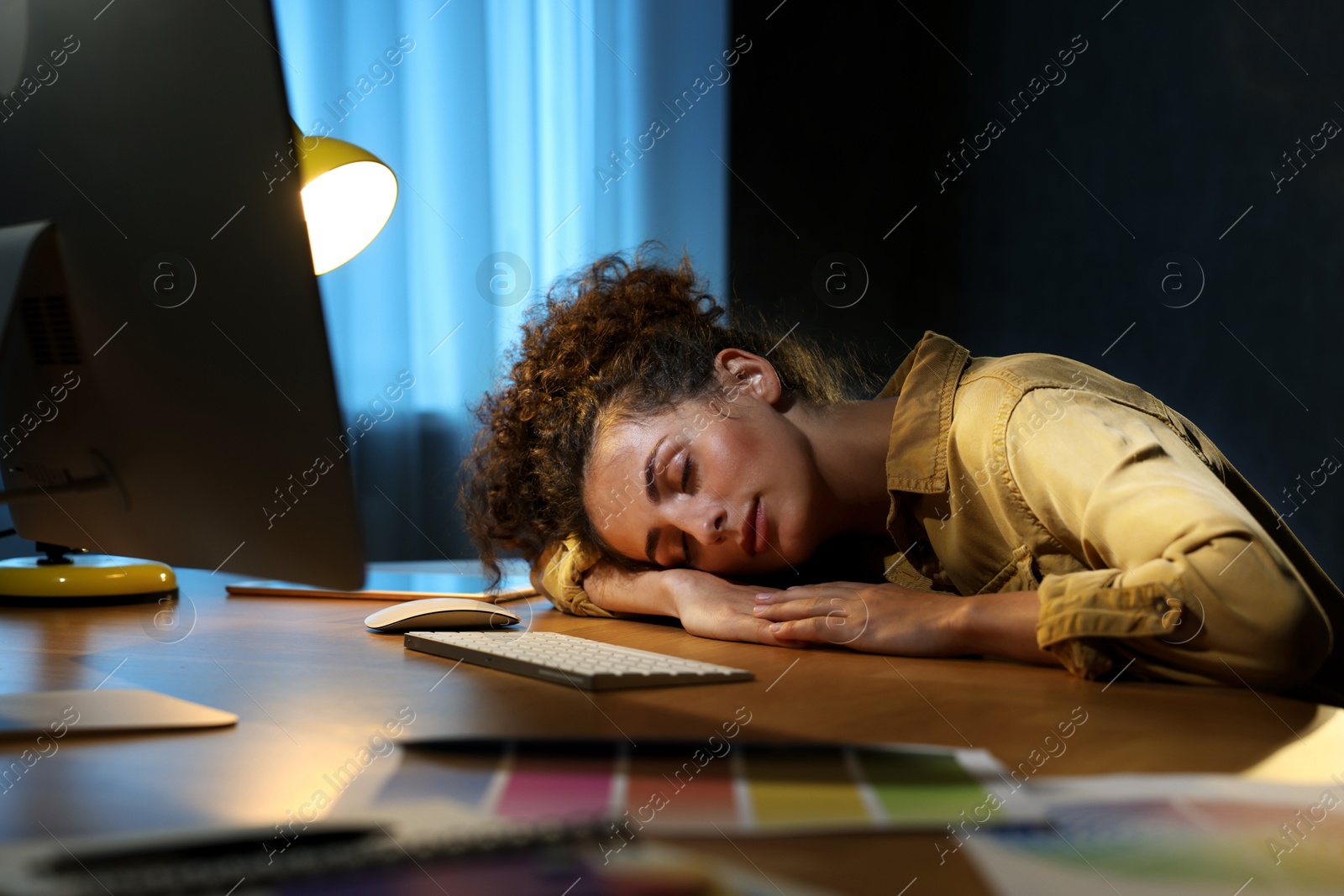 Photo of Tired designer sleeping near computer indoors at night