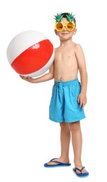 Photo of Cute little boy in beachwear with funny sunglasses and inflatable ball on white background