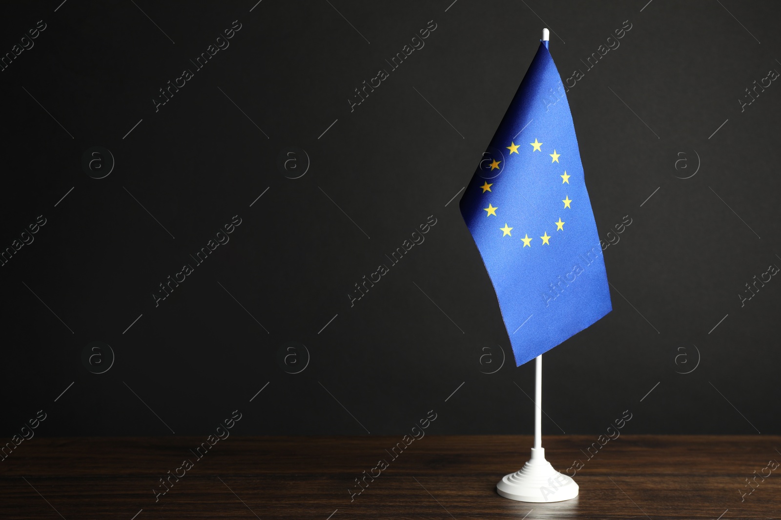 Photo of One flag of European Union on wooden table against black background. Space for text