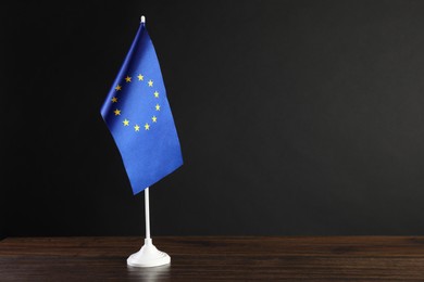 Photo of One flag of European Union on wooden table against black background. Space for text