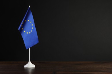 Photo of One flag of European Union on wooden table against black background. Space for text