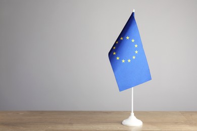 Photo of One flag of European Union on wooden table against grey background. Space for text