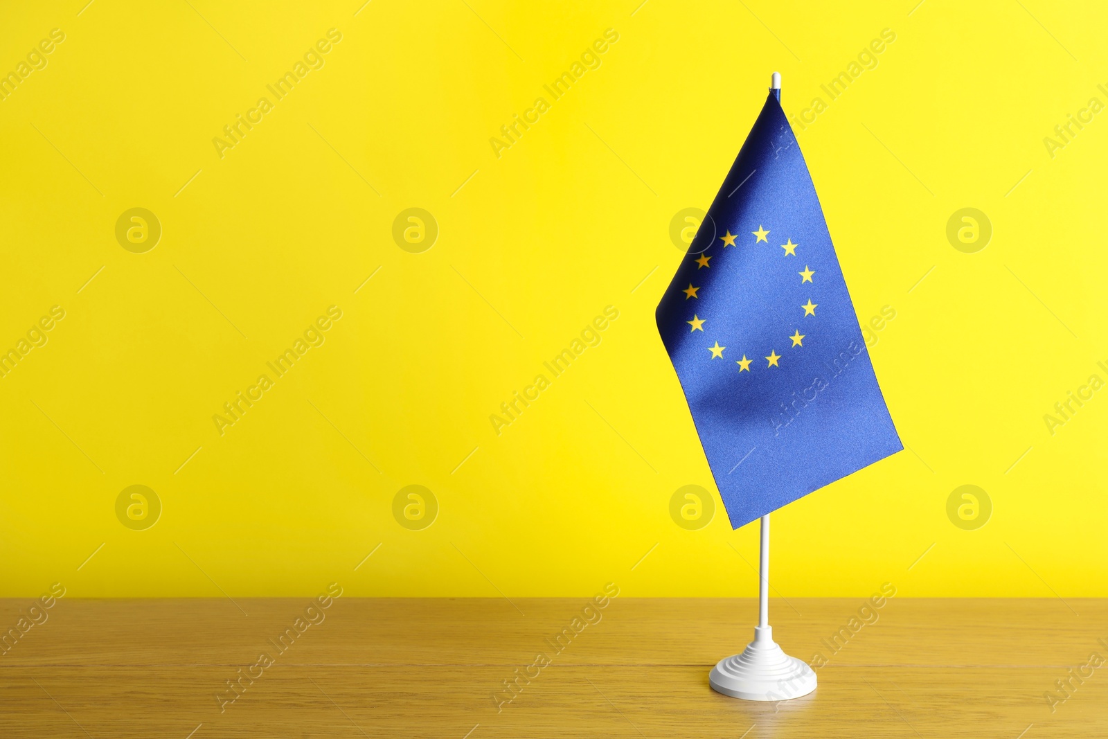 Photo of Flag of European Union on wooden table against yellow background