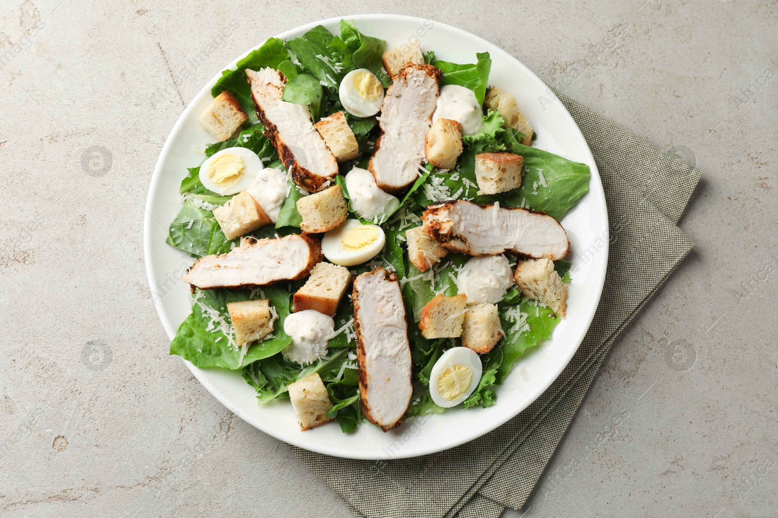 Photo of Tasty Caesar salad with chicken on light grey table, top view