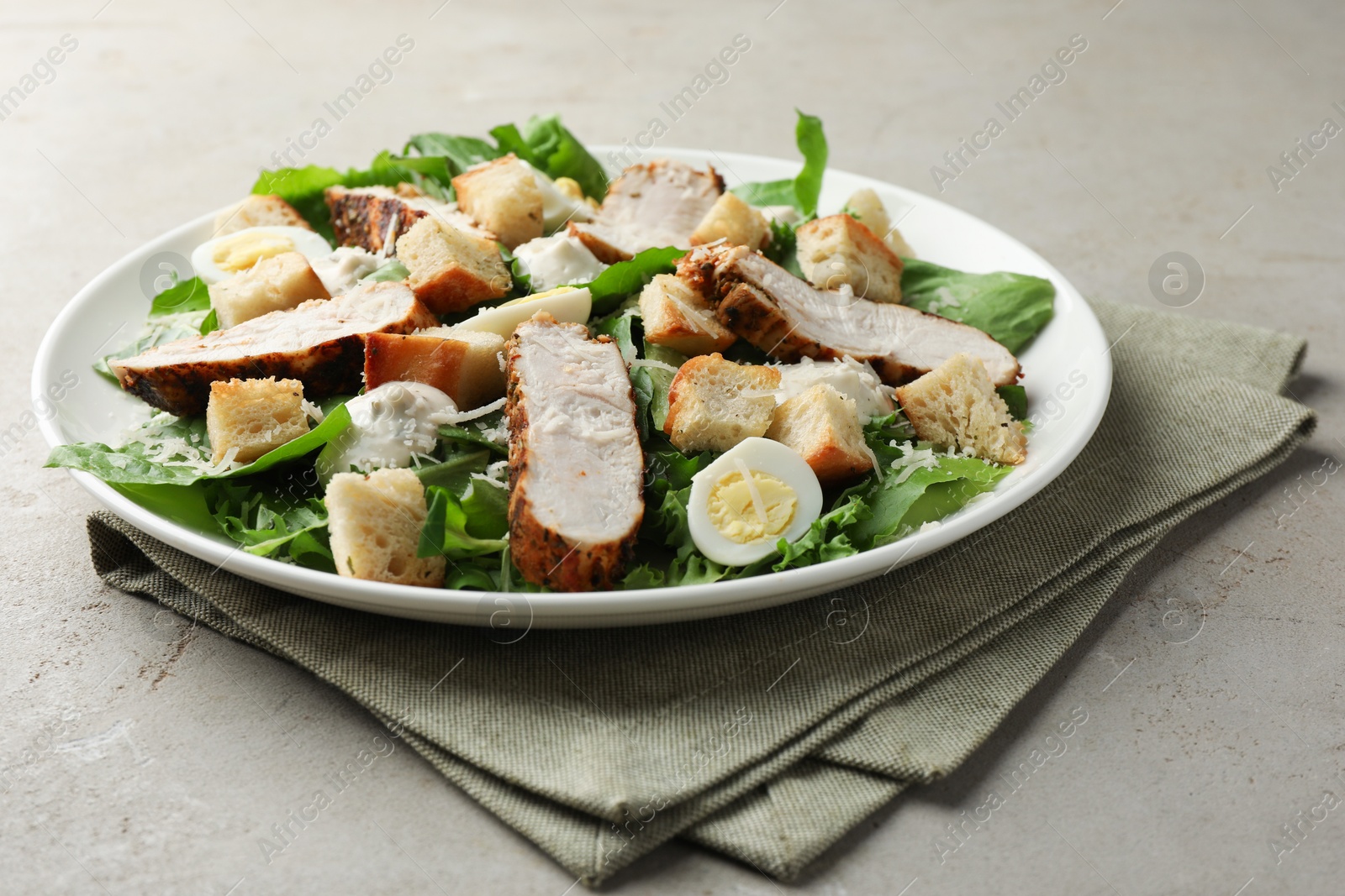 Photo of Tasty Caesar salad with chicken on light grey table