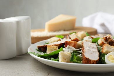 Photo of Tasty Caesar salad with chicken on light grey table, closeup