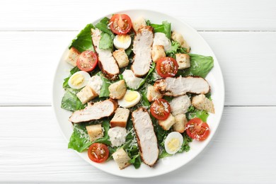 Tasty Caesar salad with chicken and tomatoes on white wooden table, top view