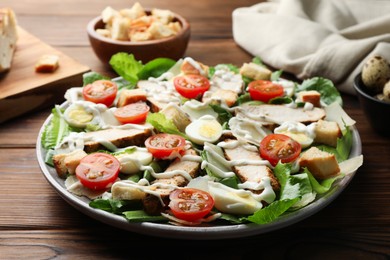 Photo of Delicious Caesar salad with chicken on wooden table, closeup