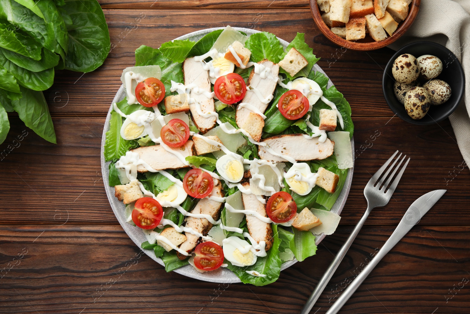 Photo of Delicious Caesar salad with chicken served on wooden table, flat lay