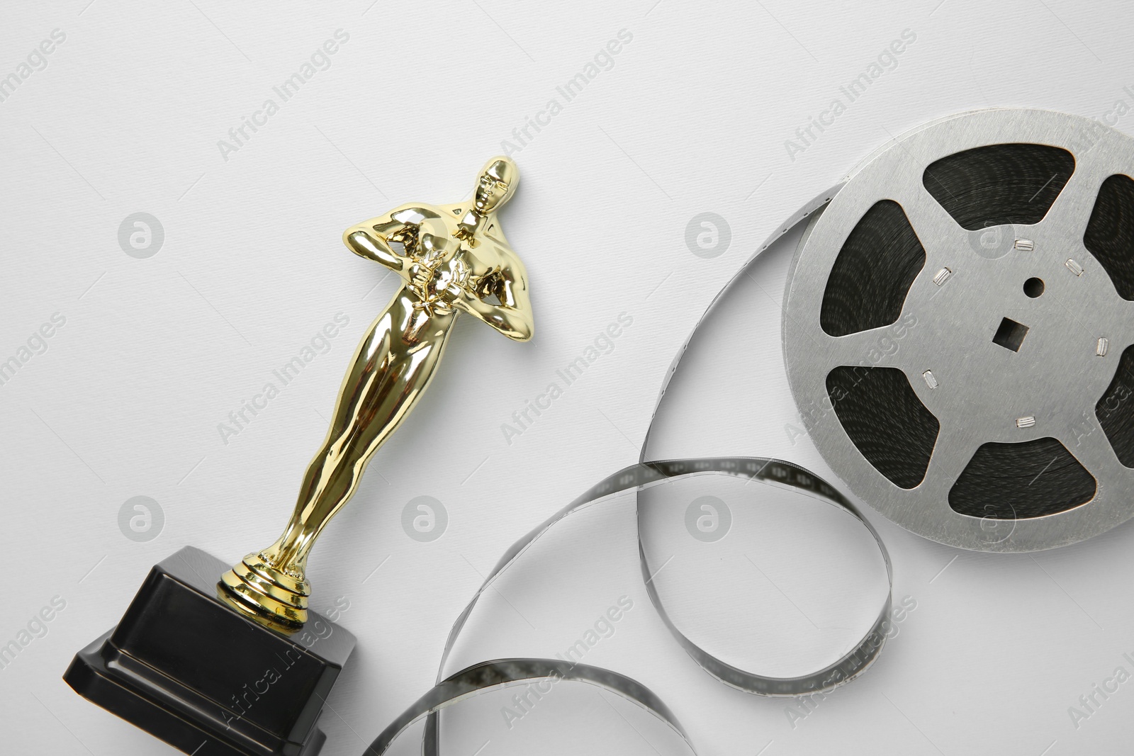 Photo of Golden trophy in shape of human figure and film reel on white background, top view