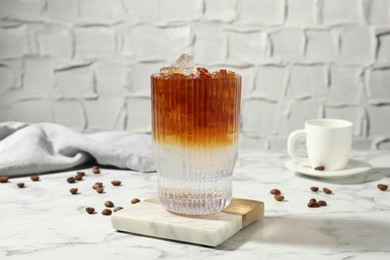 Refreshing espresso tonic drink and coffee beans on white marble table