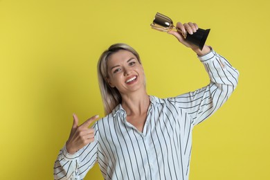 Photo of Happy winner with golden trophy cup on yellow background