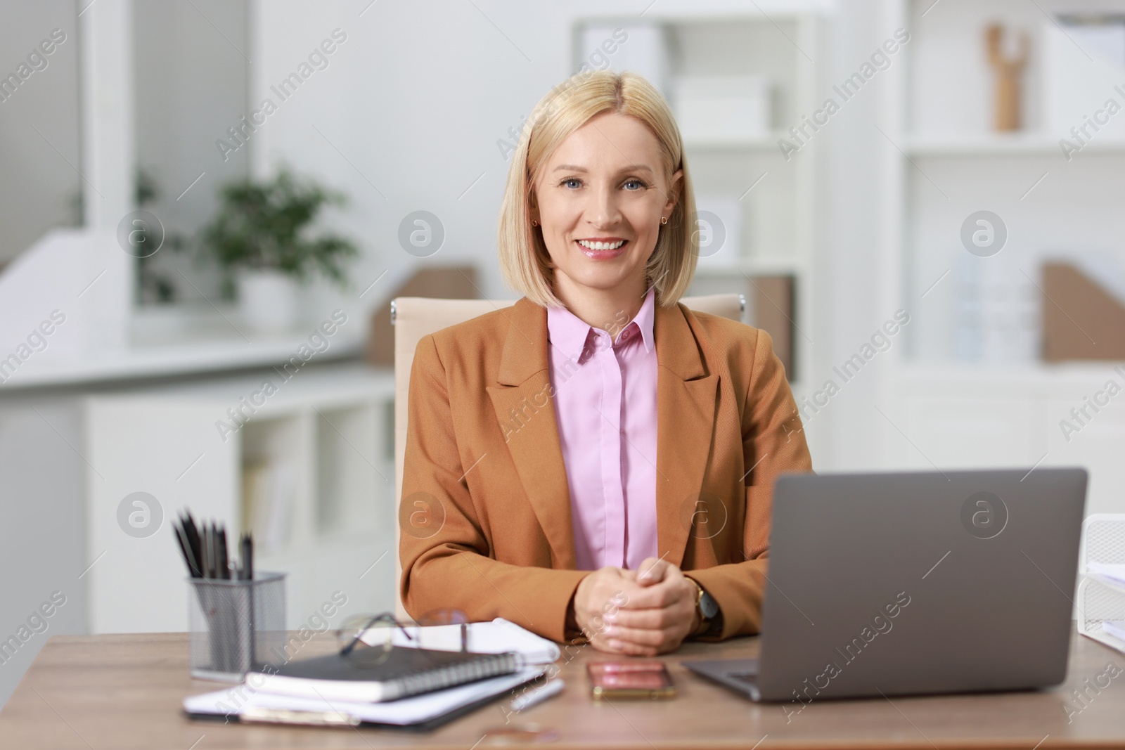 Photo of Portrait of smiling middle aged woman at table in office