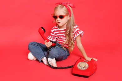 Photo of Cute little girl with telephone on red background