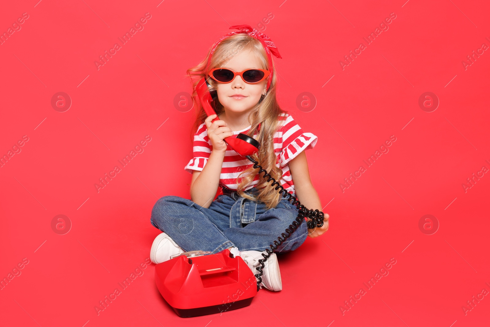 Photo of Cute little girl with telephone on red background