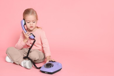 Photo of Cute little girl with telephone on pink background, space for text