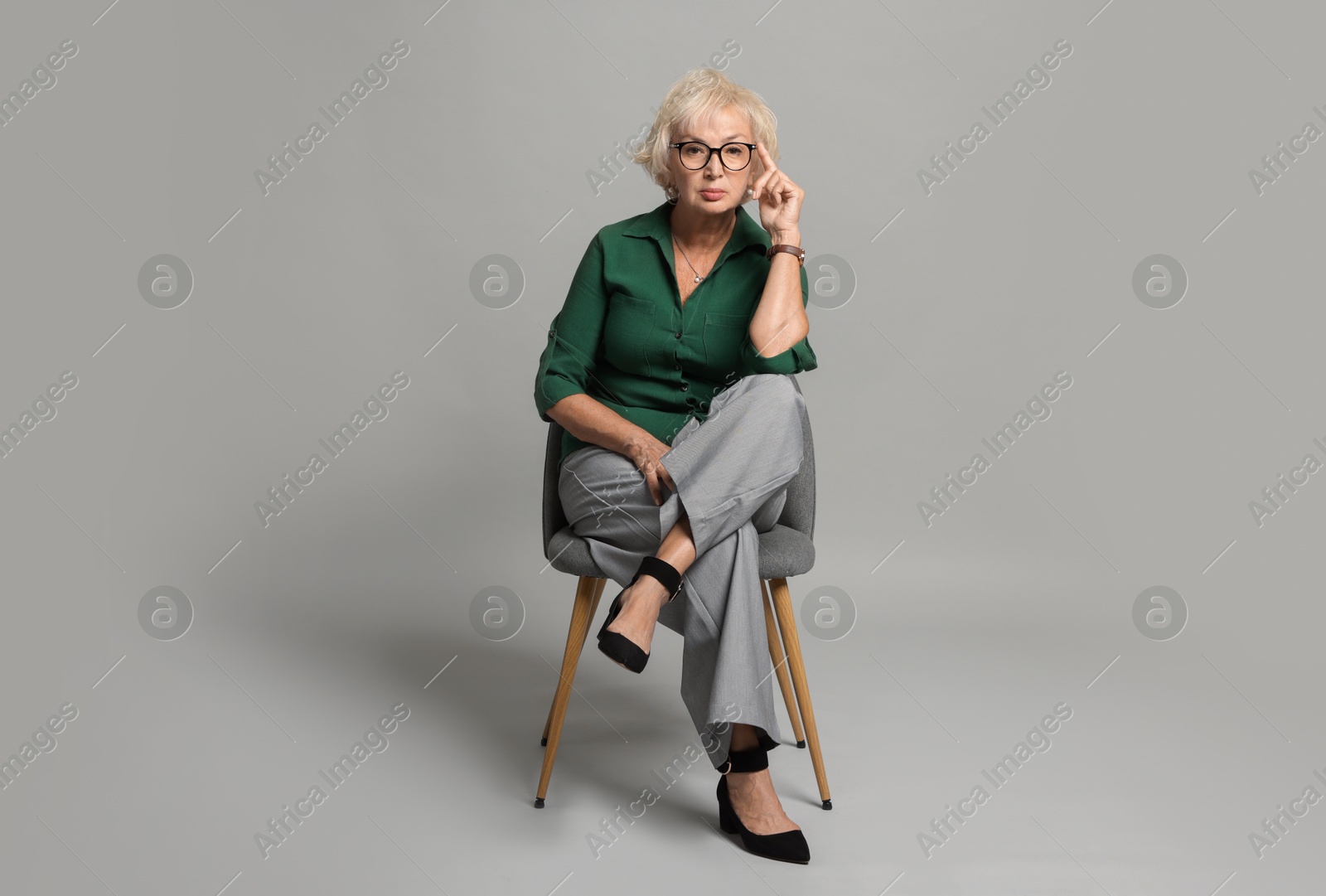 Photo of Beautiful senior woman sitting on chair against light grey background