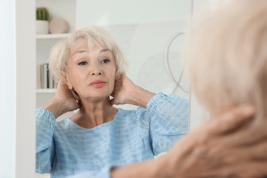 Photo of Beautiful senior woman near mirror at home