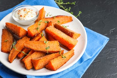 Pieces of tasty baked sweet potato with microgreens and sauce on grey textured table, closeup