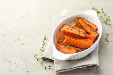 Pieces of tasty cooked sweet potato in baking dish with microgreens on light textured table. Space for text