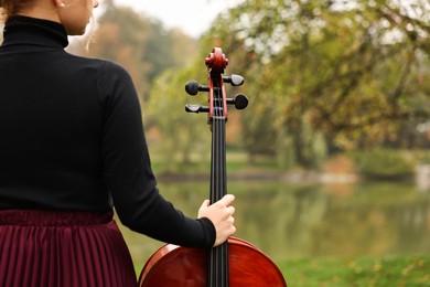 Photo of Young woman with cello in park, closeup. Space for text