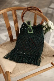 Photo of Handmade macrame shopping bag with flowers and sunglasses on chair indoors