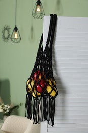 Photo of Handmade macrame shopping bag with fruits indoors