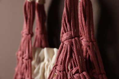 Photo of Handmade macrame shopping bag on brown wall, closeup