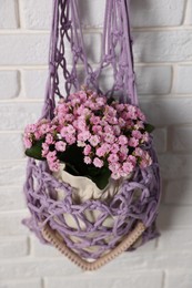 Photo of Handmade macrame shopping bag with flowers on white brick wall