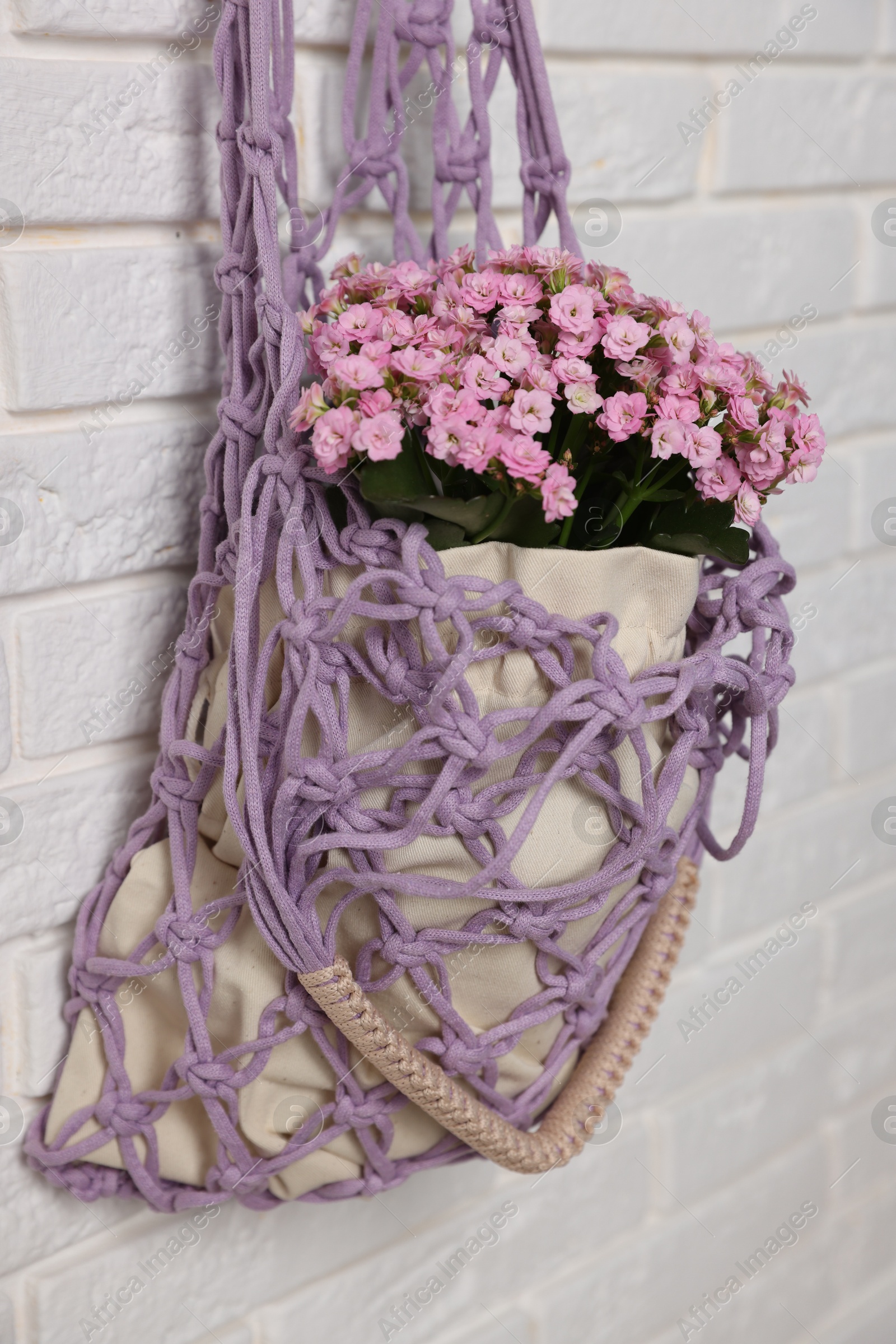 Photo of Handmade macrame shopping bag with flowers on white brick wall