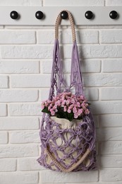 Photo of Handmade macrame shopping bag with flowers on white brick wall