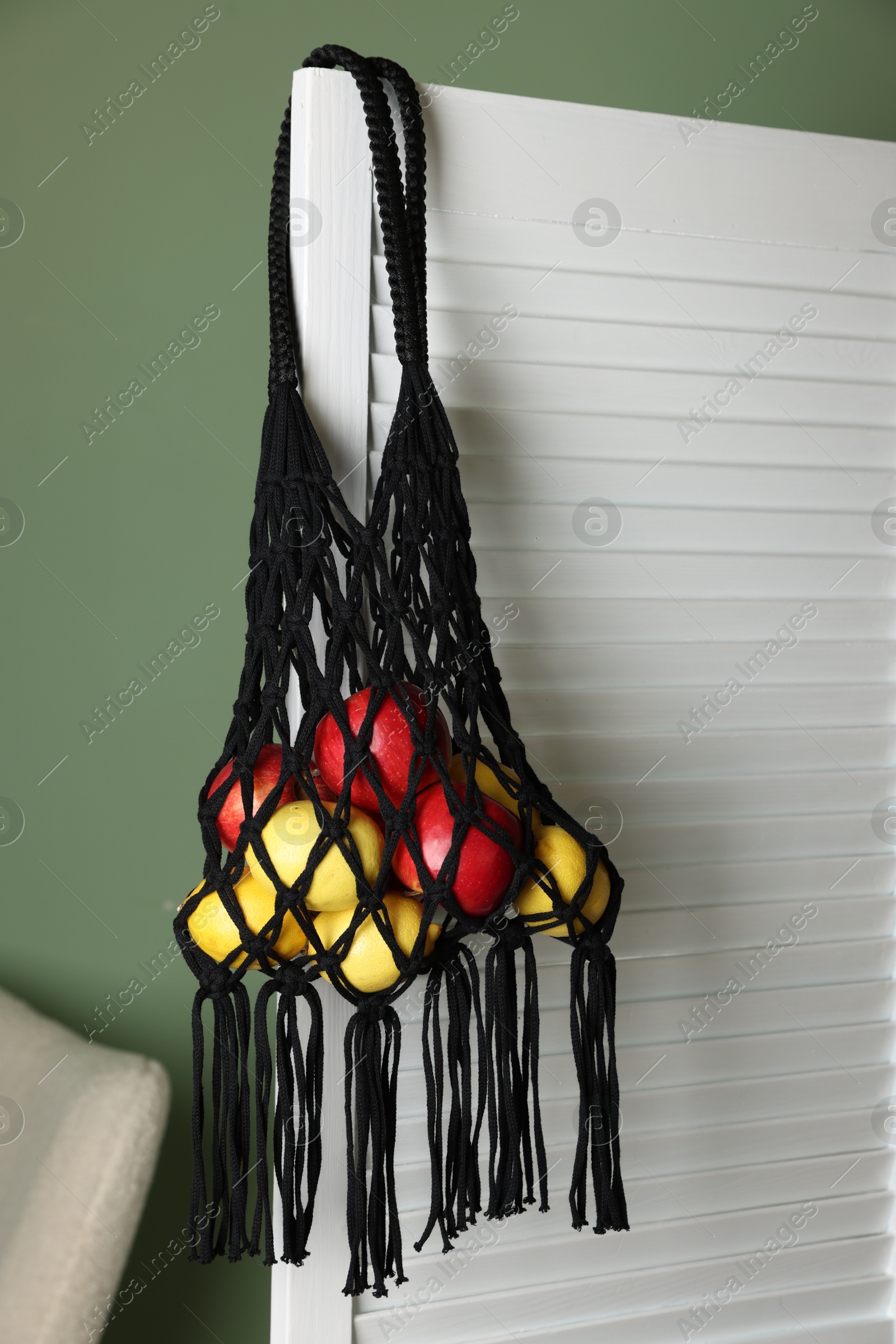 Photo of Handmade macrame shopping bag with fruits indoors