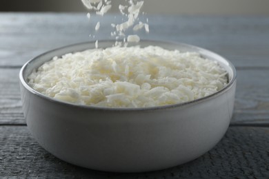 Photo of Pouring soy wax into bowl on grey wooden table, closeup