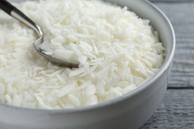 Photo of Soy wax in bowl on grey wooden table, closeup