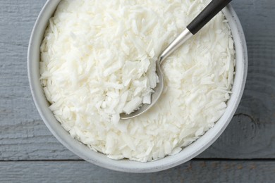 Photo of Soy wax in bowl on grey wooden table, top view