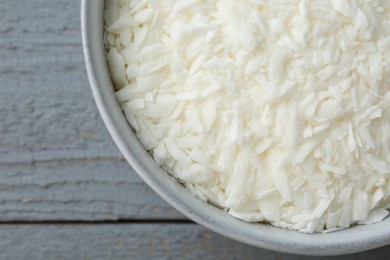 Photo of Soy wax in bowl on grey wooden table, top view