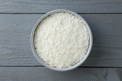 Photo of Soy wax in bowl on grey wooden table, top view