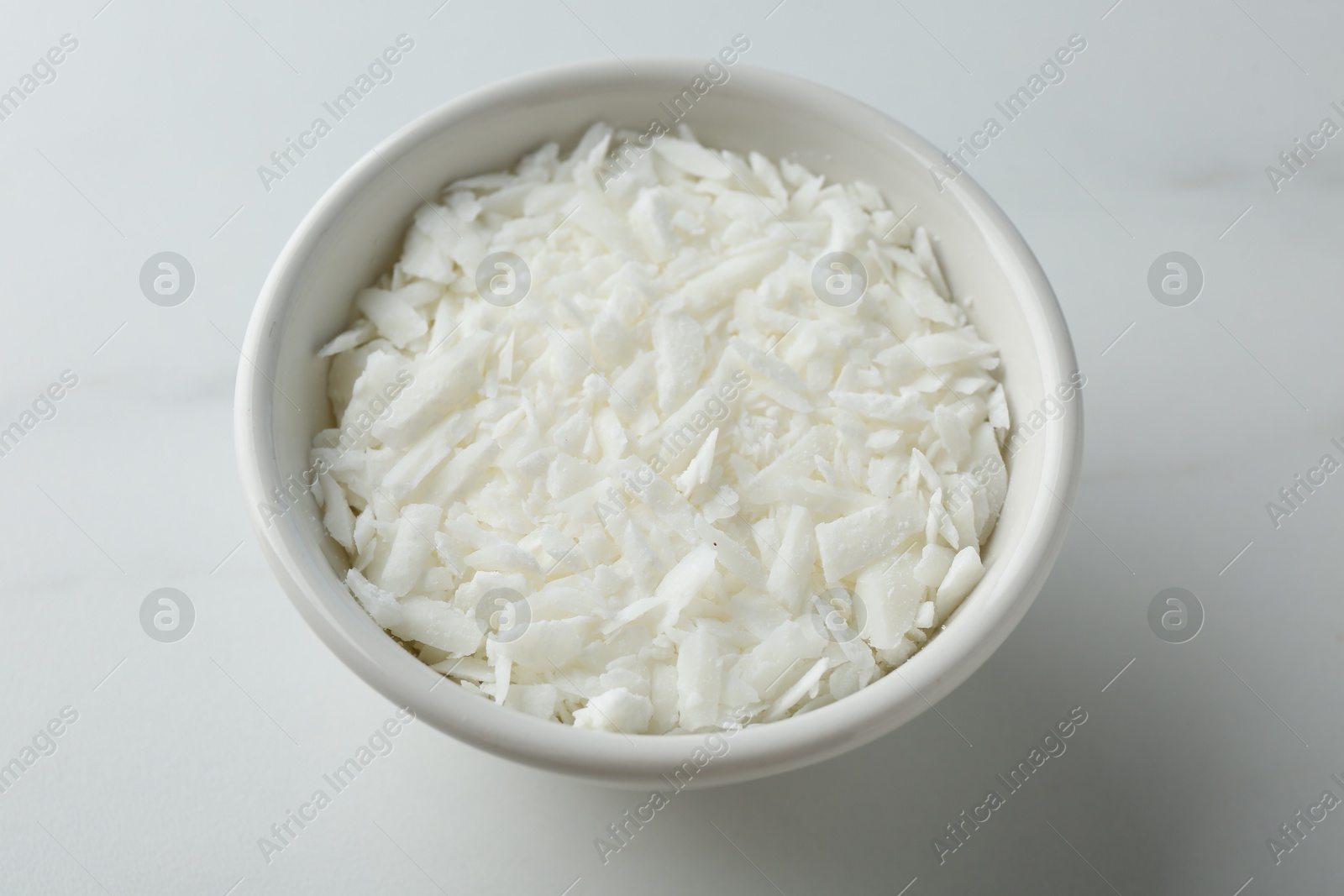 Photo of Soy wax in bowl on white marble table