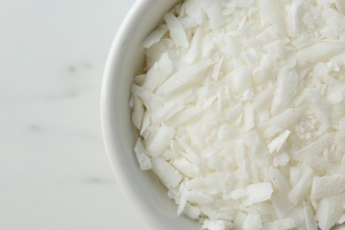 Photo of Soy wax in bowl on white marble table, top view