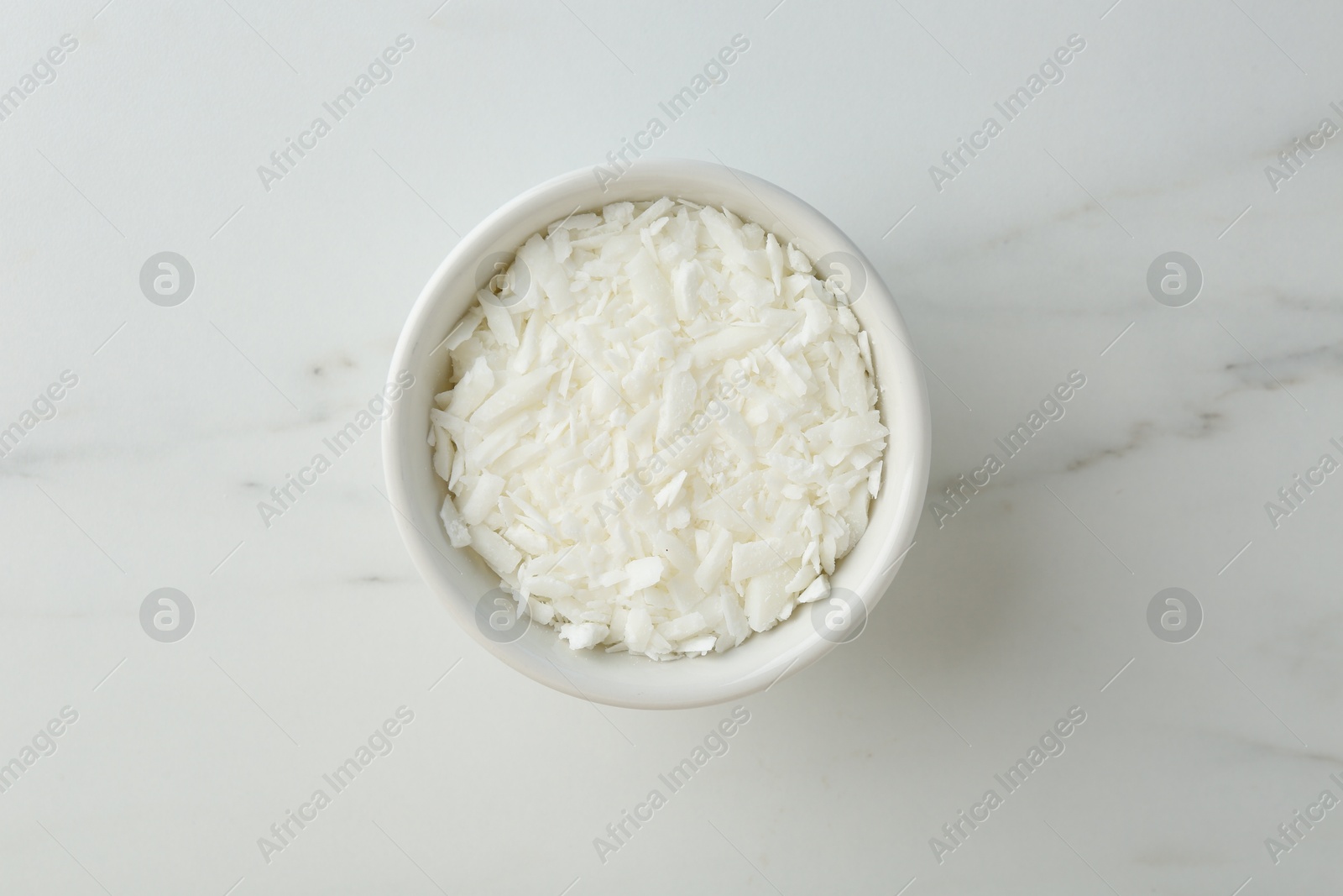 Photo of Soy wax in bowl on white marble table, top view