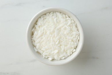 Photo of Soy wax in bowl on white marble table, top view