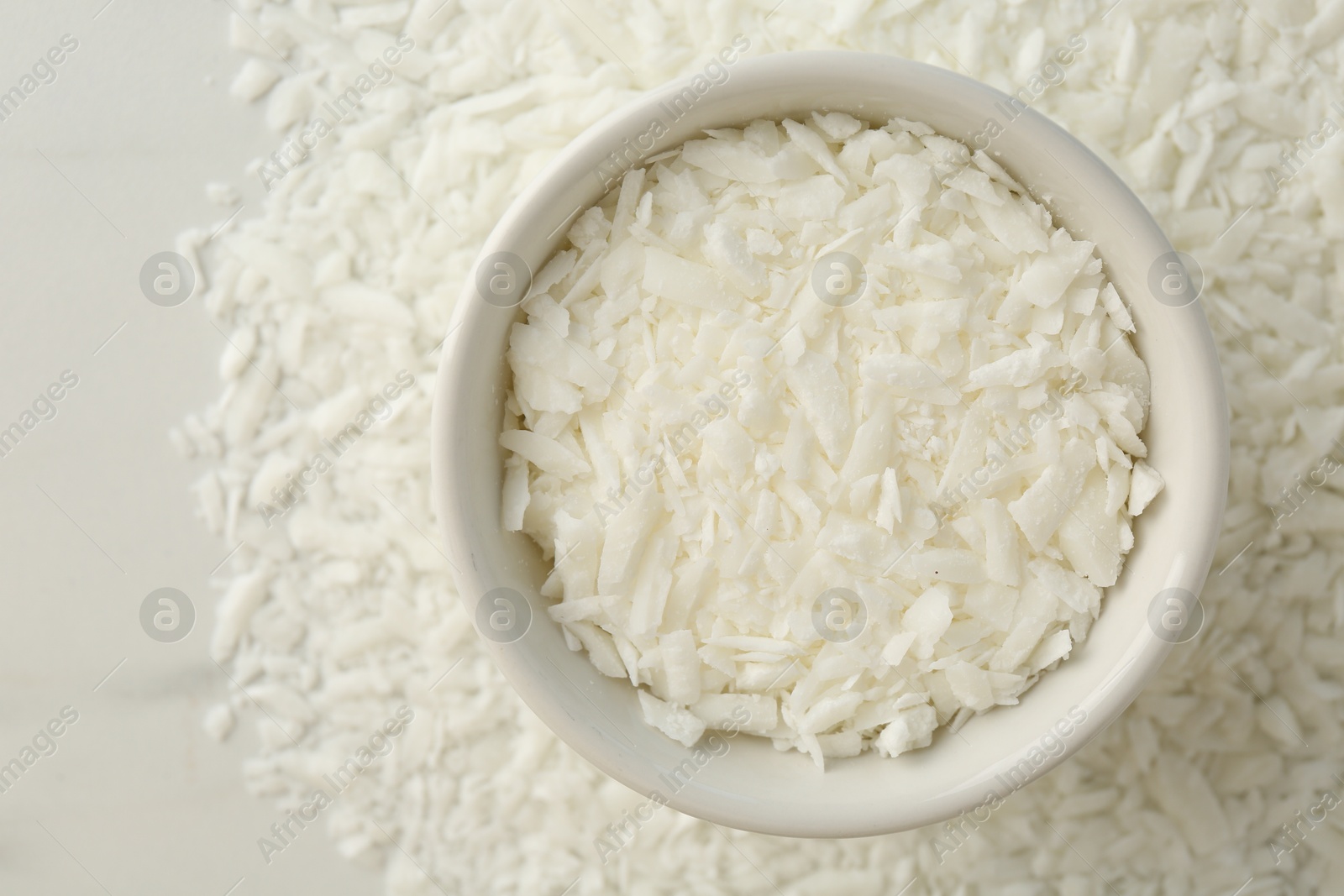 Photo of Soy wax in bowl on white table, top view