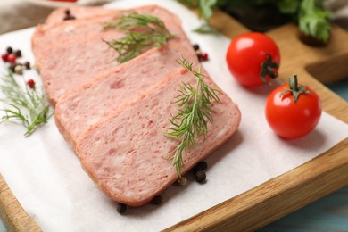 Photo of Pieces of tasty canned meat, dill, peppercorns and tomatoes on table, closeup