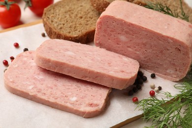 Photo of Pieces of tasty canned meat, peppercorns, dill and bread on table, closeup