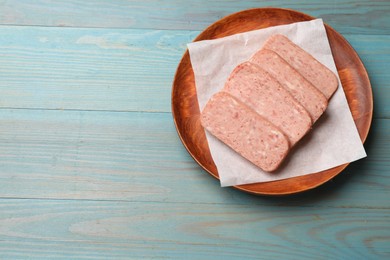 Photo of Pieces of canned meat on blue wooden table, top view. Space for text