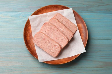 Photo of Pieces of canned meat on blue wooden table, top view