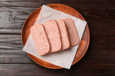 Photo of Pieces of canned meat on wooden table, top view