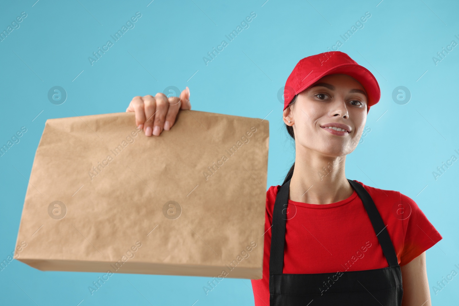 Photo of Fast-food worker with paper bag on light blue background