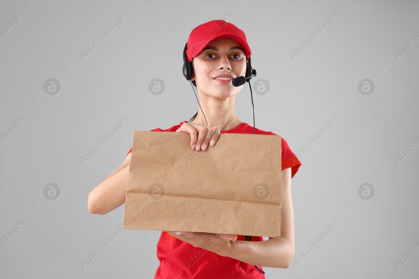 Photo of Fast-food worker with paper bag on gray background