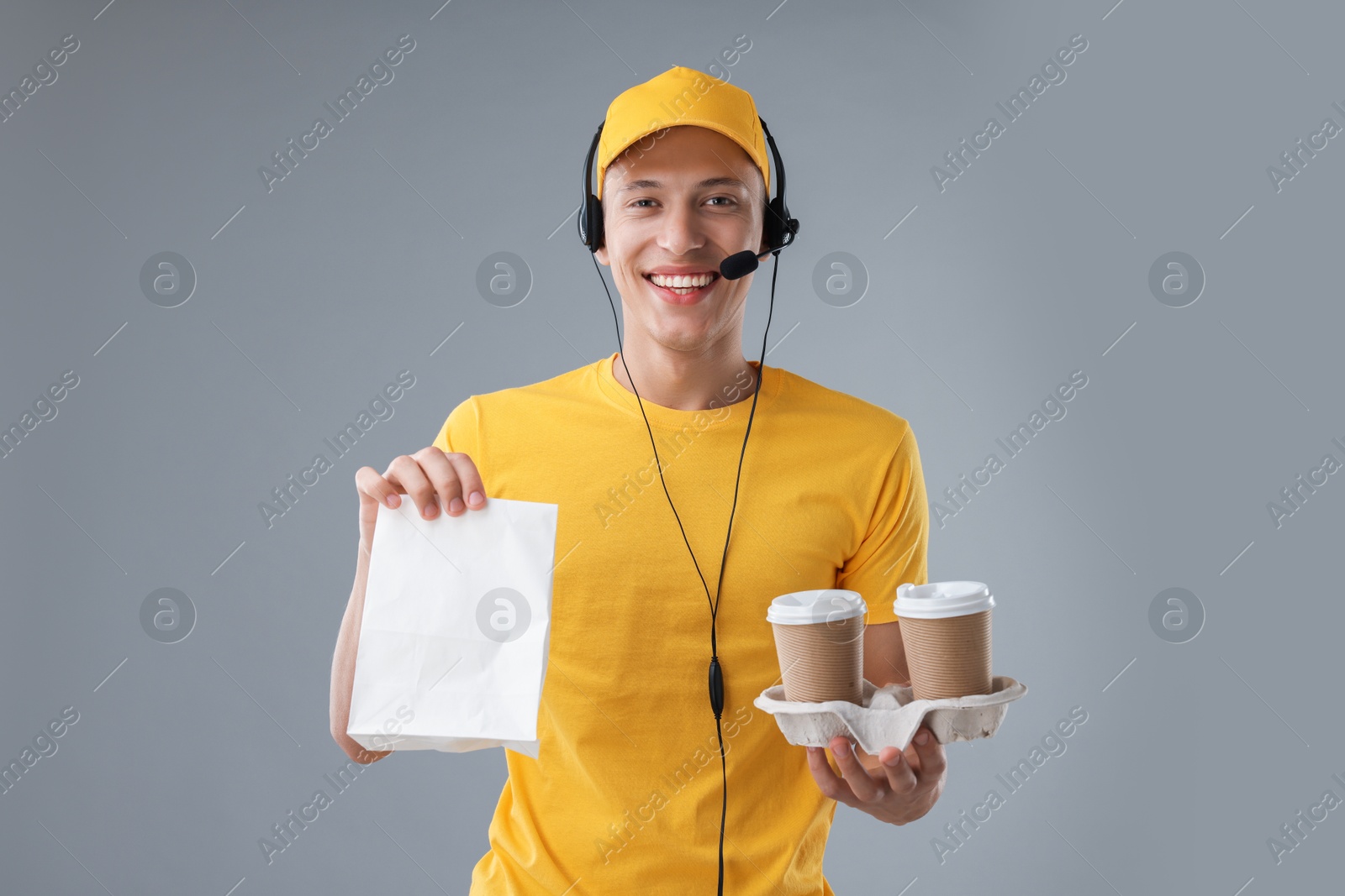 Photo of Fast-food worker with paper bag and cups on gray background